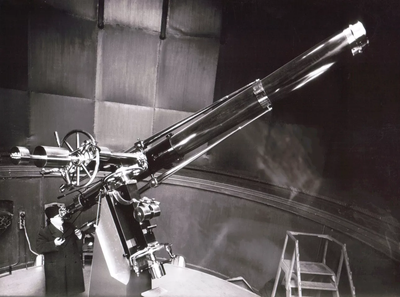 Astronomer looking through a large telescope tube. Photo.